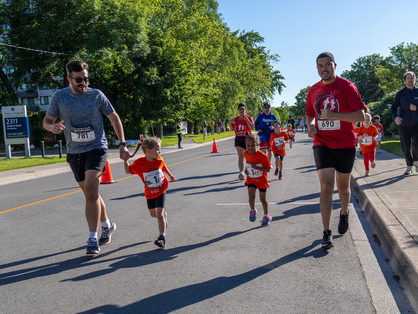 A dad running hand-in-hand with his kids during the Kids 1K at the Mercedes-Benz Oakville Bronte Harbour Classic on Father's Day, Bronte Heritage Waterfront Park, Oakville